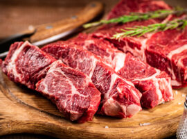 Raw beef on a cutting board with rosemary and spices.